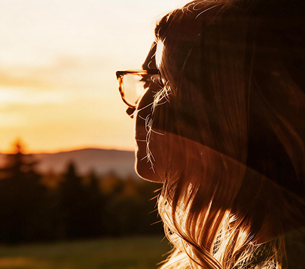 A woman wearing high prescription glasses at sunset