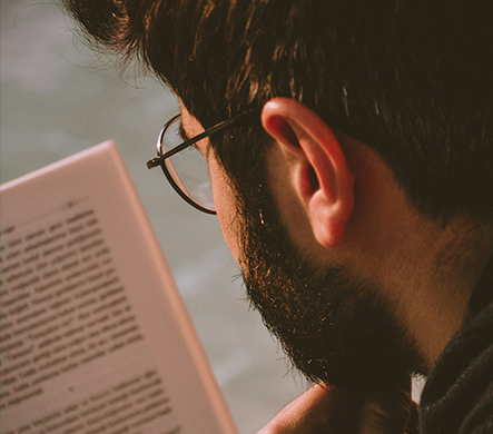 A man wearing reading glasses reading a book